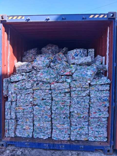 Contenedor con balas de latas apiladas
